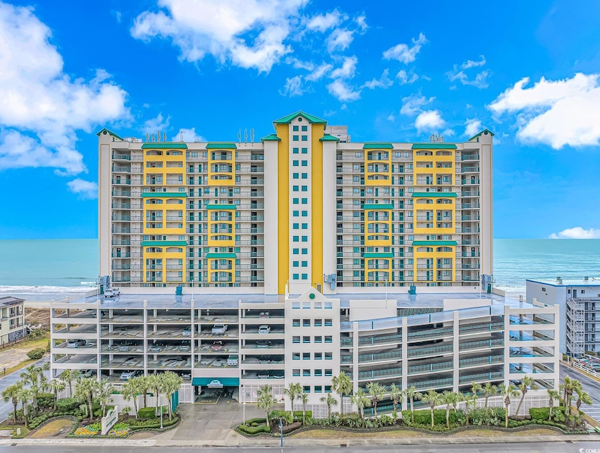 View of apartment building / complex featuring view of water and beach