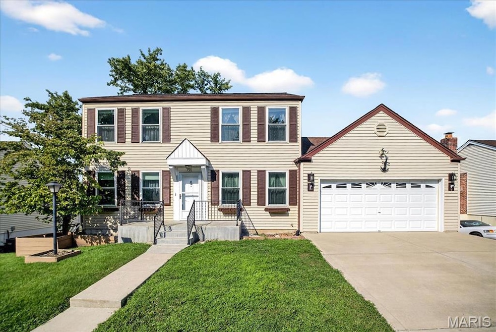 Colonial house featuring a front yard, driveway, and a garage
