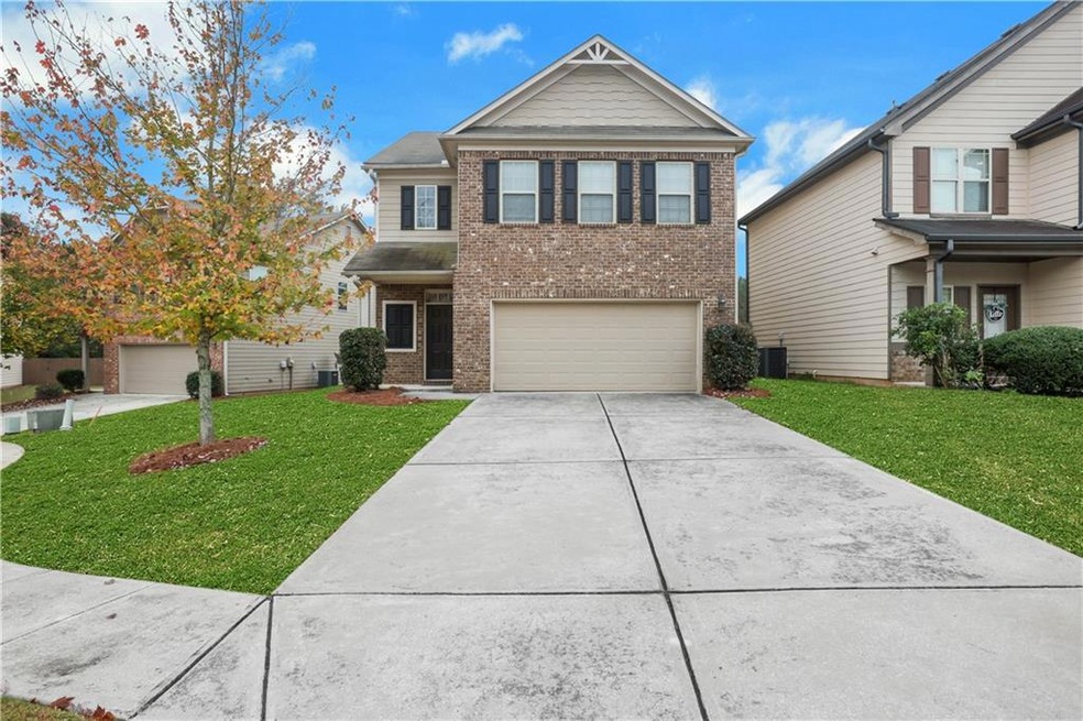 View of front of house with a garage, a front yard, and central AC