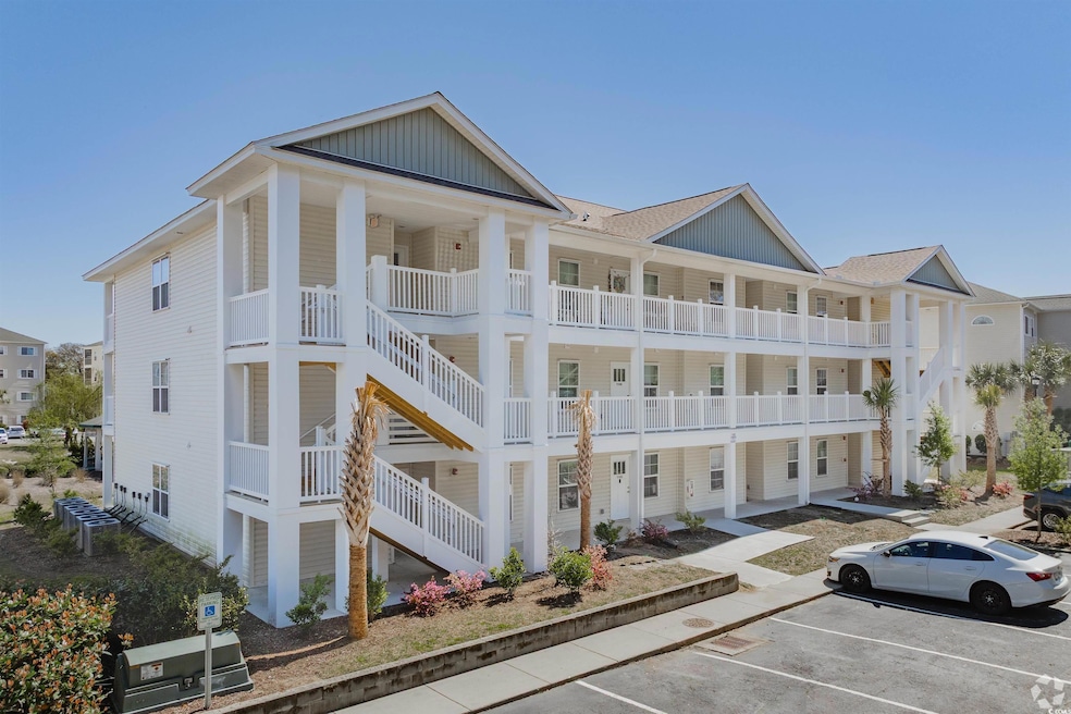 View of building exterior with uncovered parking and stairway