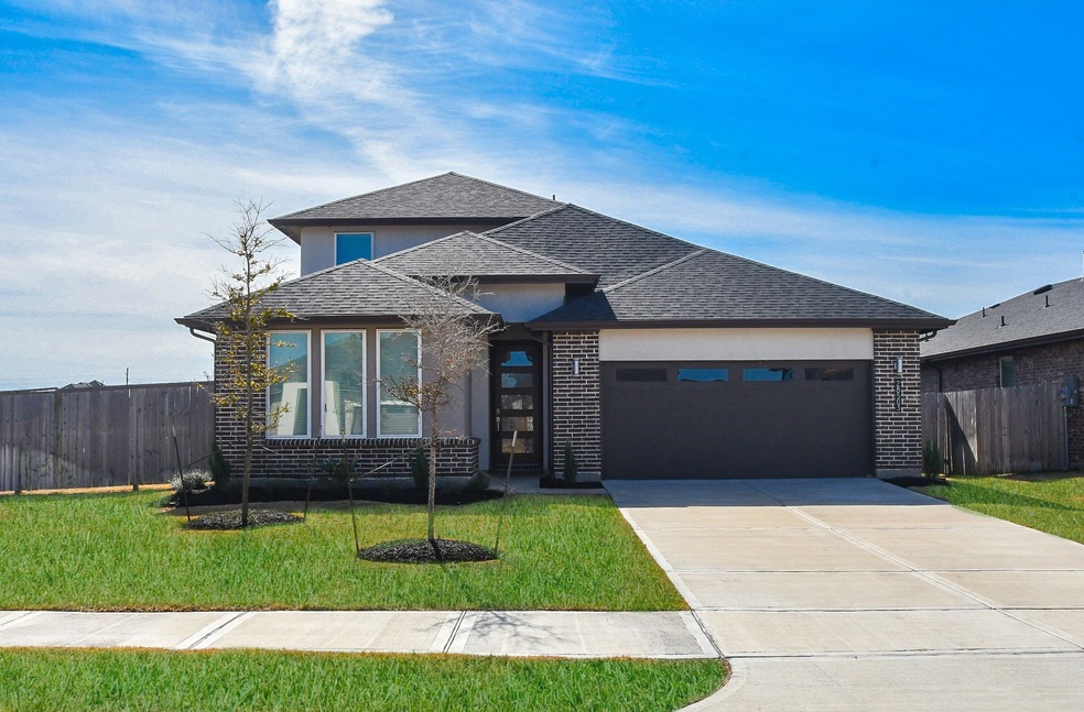 This sleek, contemporary brick RENTAL home offers all the luxurious amenities you're looking for! Seen here, is the dual-vehicle attached garage atop its pristine, driveway with a glimpse of the lovely covered front entrance, left. The home is located at 28503 Hazel Trail, Katy, TX, in the new, vibrant Tamarron community.