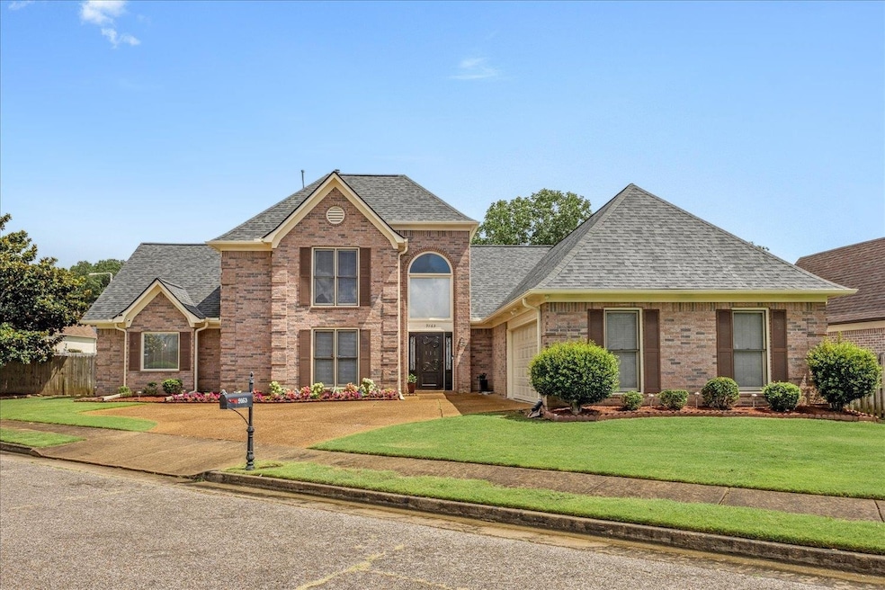 Traditional-style home featuring a shingled roof, brick siding, and a garage