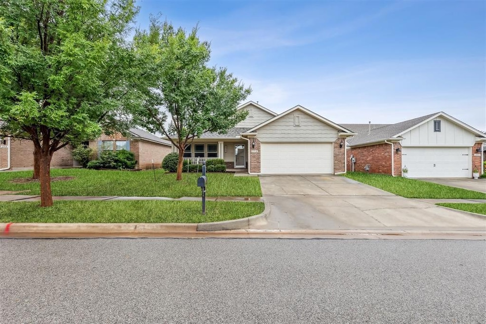 Front facade with brick siding, a front yard, an attached garage, and concrete driveway