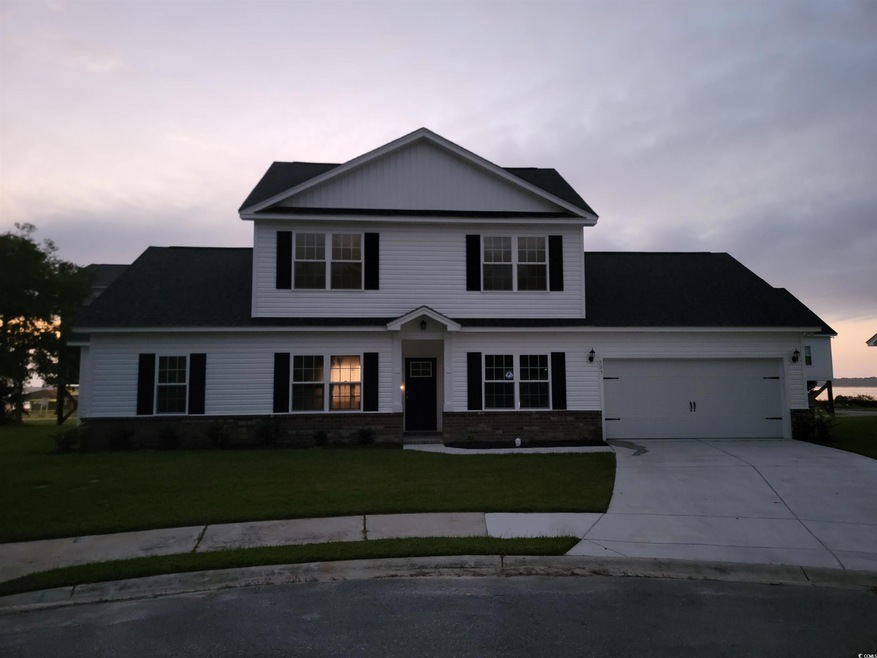 View of front facade featuring a garage and a yard