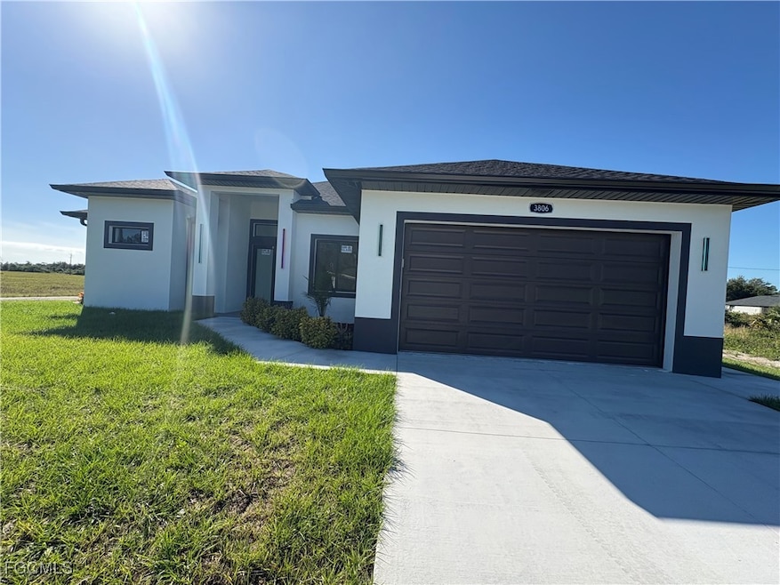 Prairie-style home with stucco siding, driveway, and a front lawn