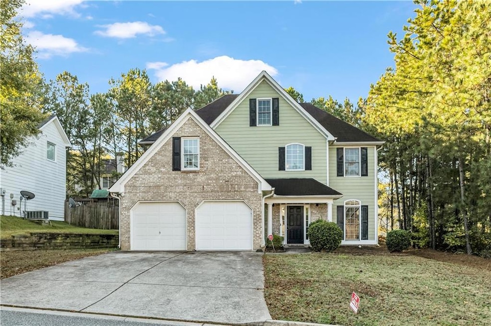 Traditional-style house featuring driveway, brick siding, and a garage