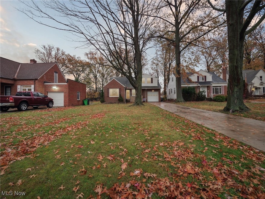 View of grassy yard featuring a garage and driveway