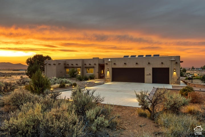 Pueblo-style house with driveway, an attached garage, and stucco siding