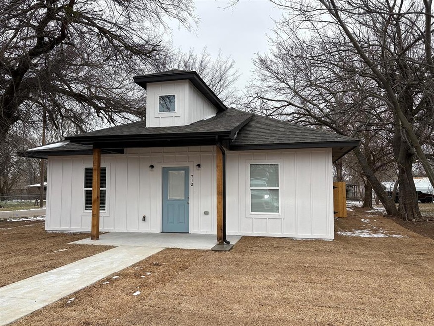 View of front of property with a shingled roof, board and batten siding, and a front lawn