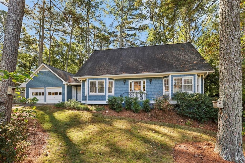 Cape cod home with a front yard, a garage, and roof with shingles
