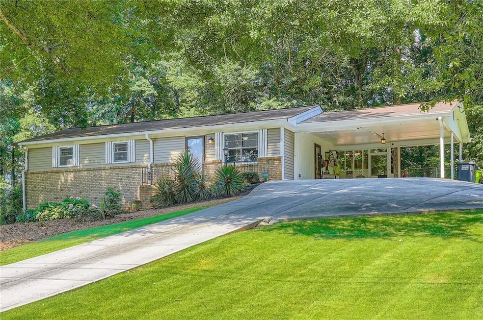View of front of property featuring concrete driveway, brick siding, a front yard, and a carport