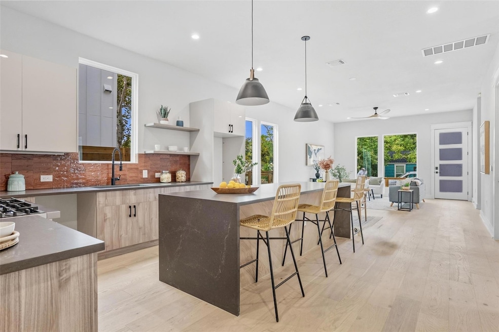 Kitchen with open shelves, a kitchen island, recessed lighting, a kitchen breakfast bar, and light wood finished floors