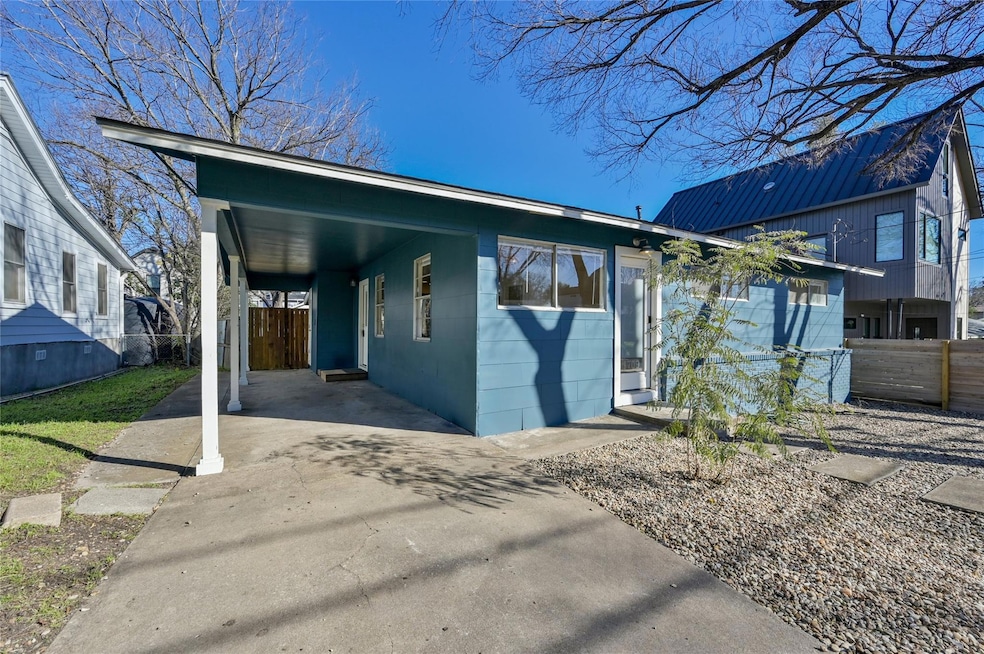 View of front facade with a carport, driveway, a patio, and a metal roof