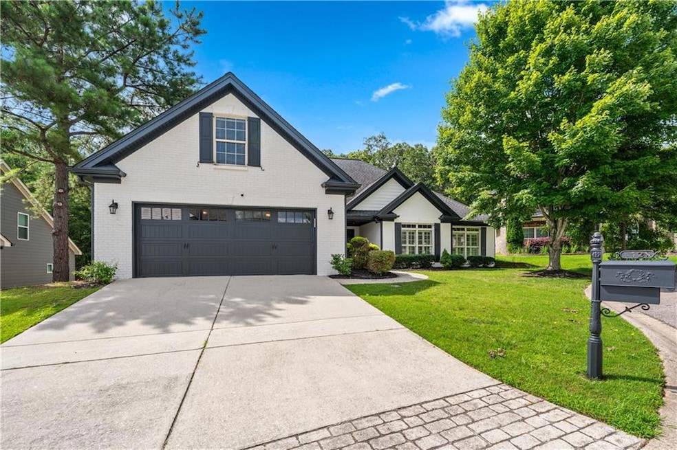 View of front facade featuring brick siding, driveway, a front yard, and an attached garage