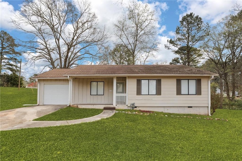 Single story home with a garage and a front lawn