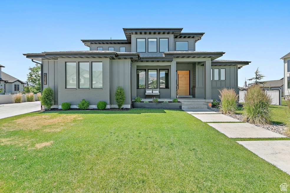View of front of property with board and batten siding, a front yard, and brick siding