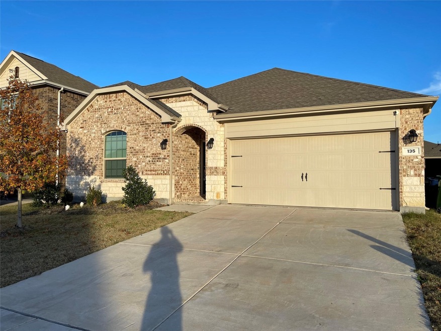 View of front of property featuring a shingled roof, a garage, brick siding, and concrete driveway
