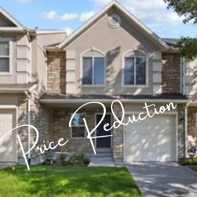 View of front of house featuring an attached garage, stone siding, driveway, covered porch, and stucco siding