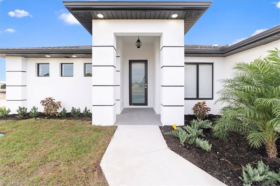 View of exterior entry with stucco siding and a yard