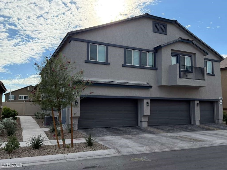 View of front of property featuring stucco siding, a balcony, an attached garage, and decorative driveway