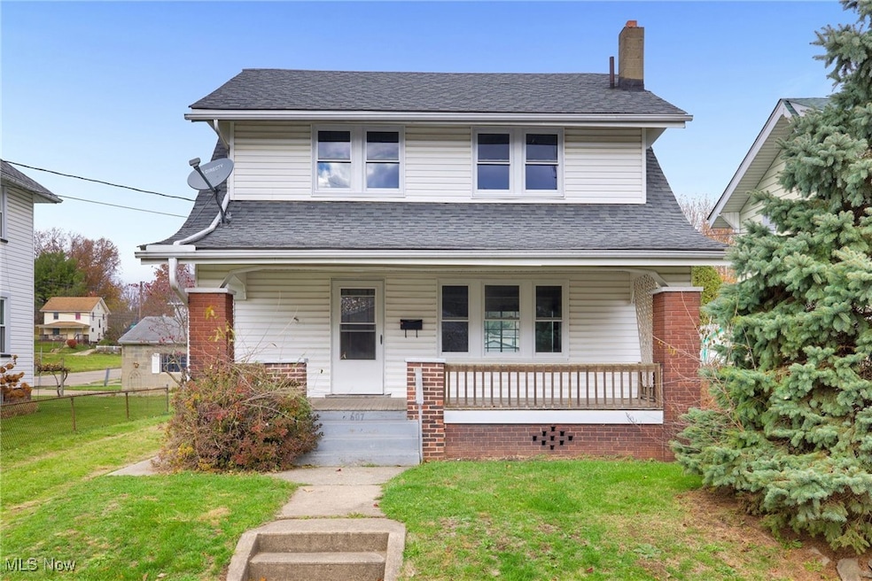 View of front of home featuring a front yard, covered porch, roof with shingles, and a chimney