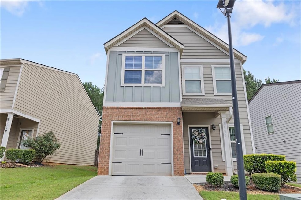 View of front of house featuring brick siding, an attached garage, board and batten siding, concrete driveway, and a front lawn