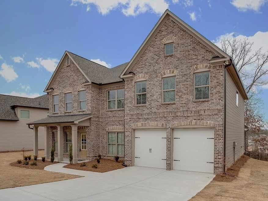 View of front of home with a porch, brick siding, concrete driveway, and an attached garage