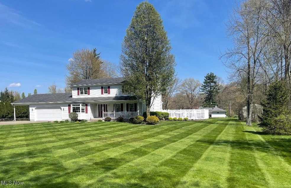View of front of property featuring covered porch, a front lawn, and an attached garage