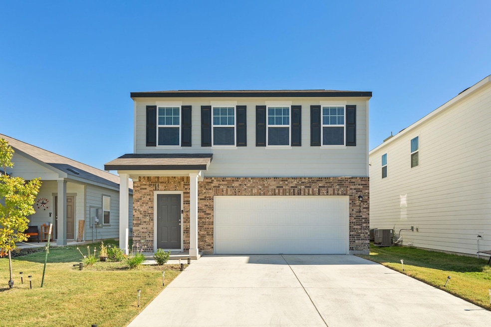 View of front of home with a front yard, driveway, an attached garage, and brick siding