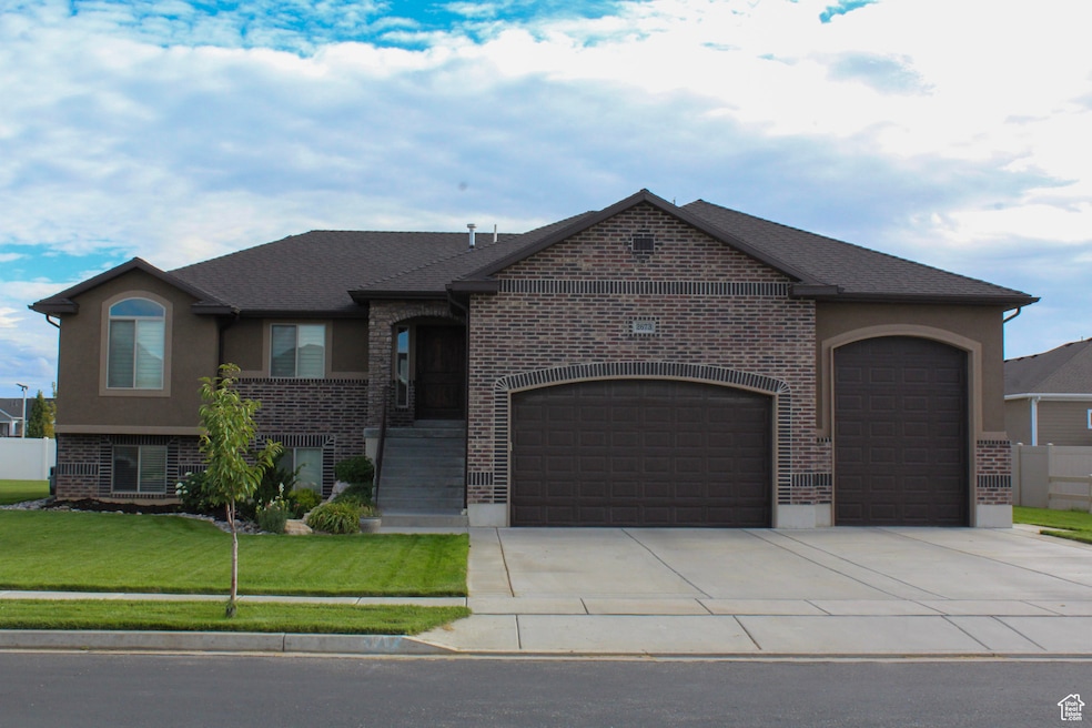 View of front facade featuring a garage, concrete driveway, brick siding, a front yard, and stucco siding