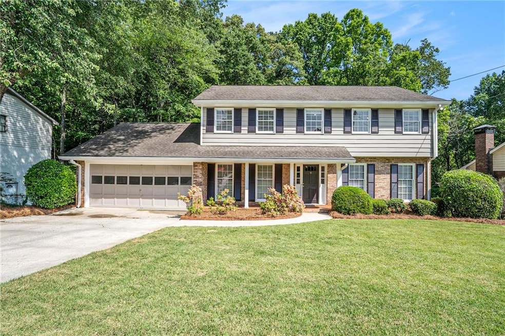 View of front of home with concrete driveway, a garage, a porch, a front lawn, and brick siding