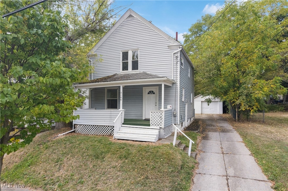 Traditional style home with covered porch, a front yard, a garage, an outdoor structure, and driveway
