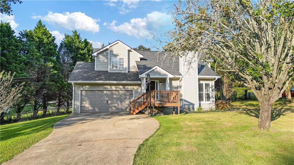 View of front of house featuring a shingled roof, driveway, a front lawn, and an attached garage