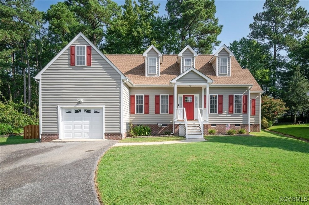 Cape cod home featuring a garage and a front yard