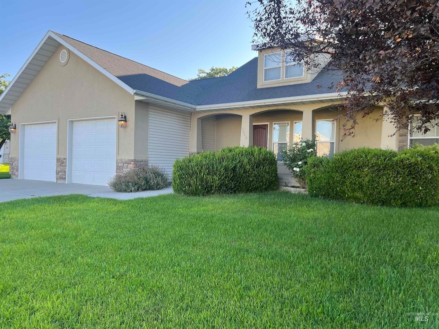 View of front of property featuring a front yard, an attached garage, stucco siding, covered porch, and stone siding