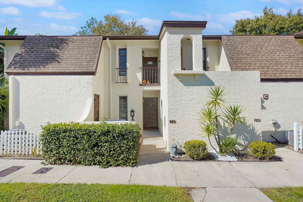 View of front of property with a balcony, stucco siding, and a shingled roof