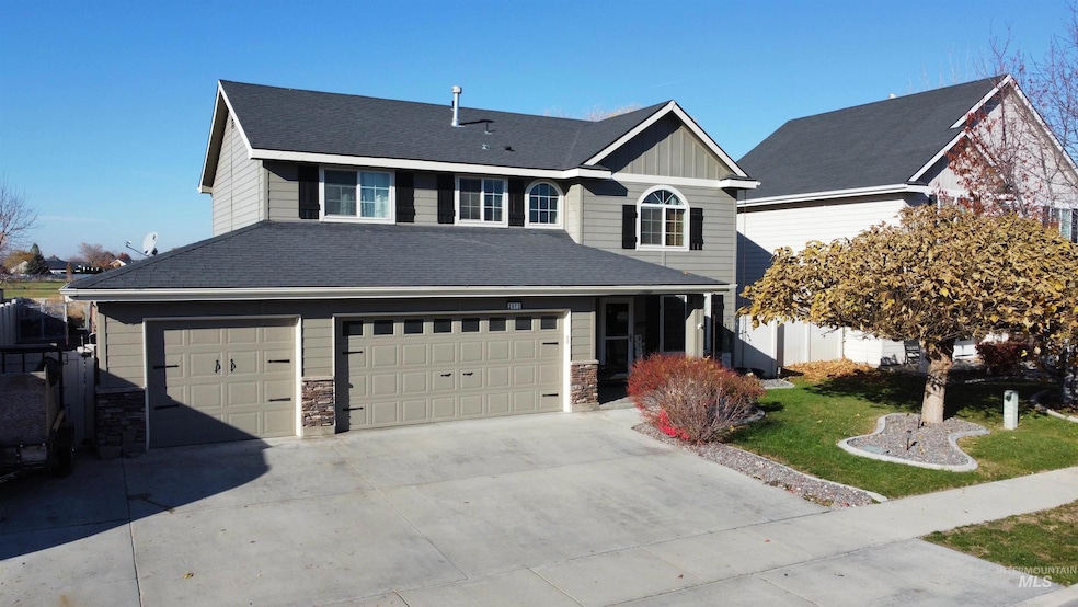 Traditional-style home featuring a front lawn, driveway, board and batten siding, a garage, and stone siding