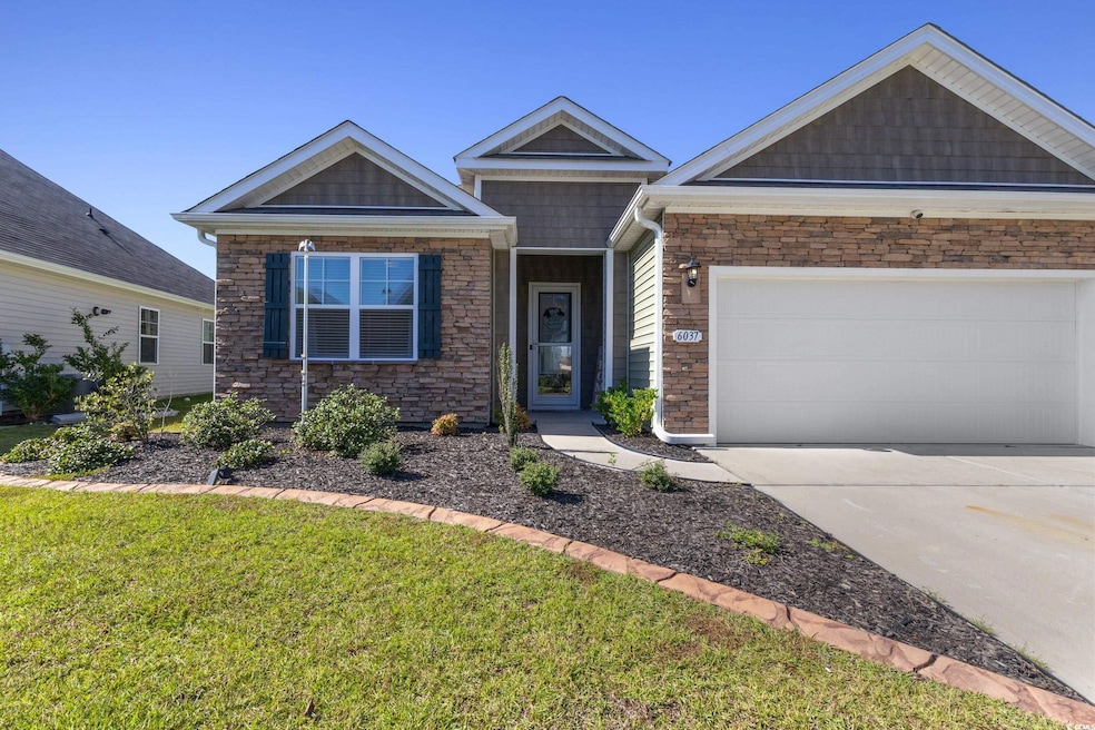 View of front of home with stone siding, driveway, an attached garage, and a front yard