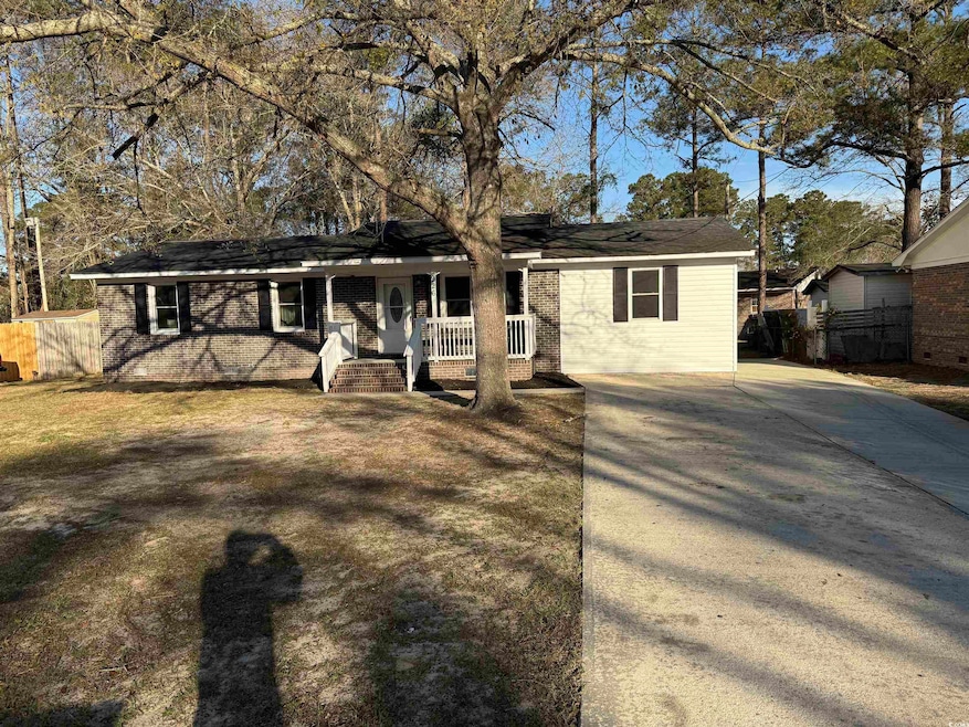 View of front of home with a porch, fence, and dri