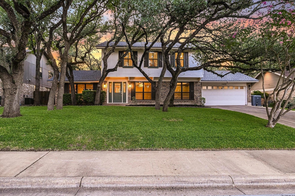 View of front of house featuring a lawn, concrete driveway, covered porch, brick siding, and an attached garage