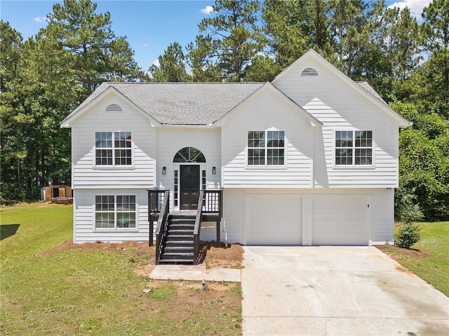 Split foyer home featuring an attached garage, a front yard, concrete driveway, and roof with shingles