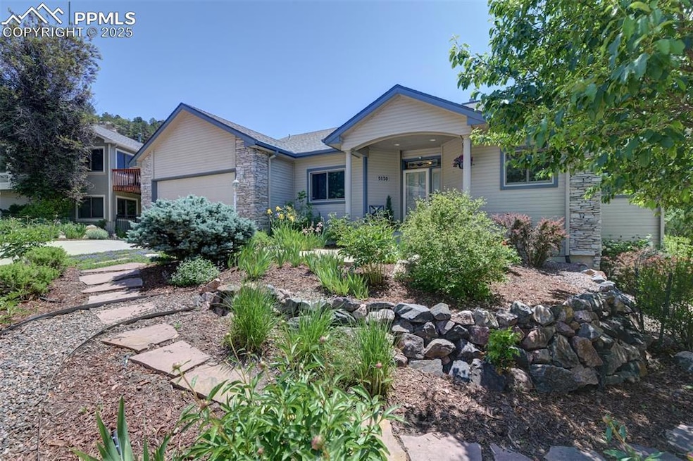 Single story home with stone siding, an attached garage, and covered porch