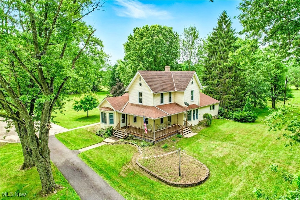 Country-style home with a porch, a chimney, driveway, a front yard, and roof with shingles