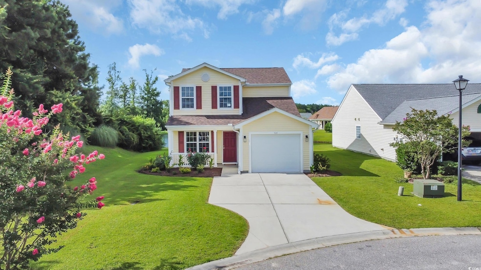 Traditional-style home with driveway, a front yard, an attached garage, and a shingled roof