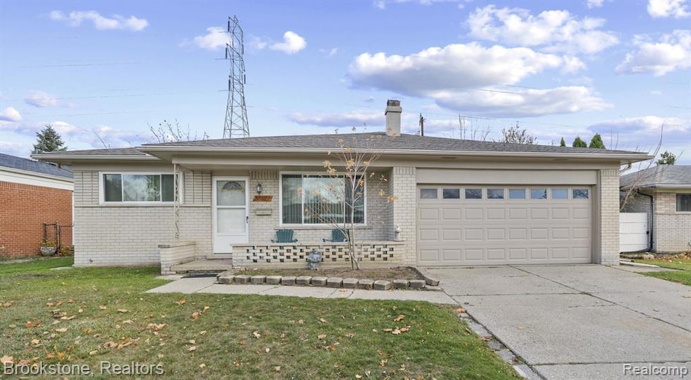 Ranch-style house featuring driveway, brick siding, and a front yard