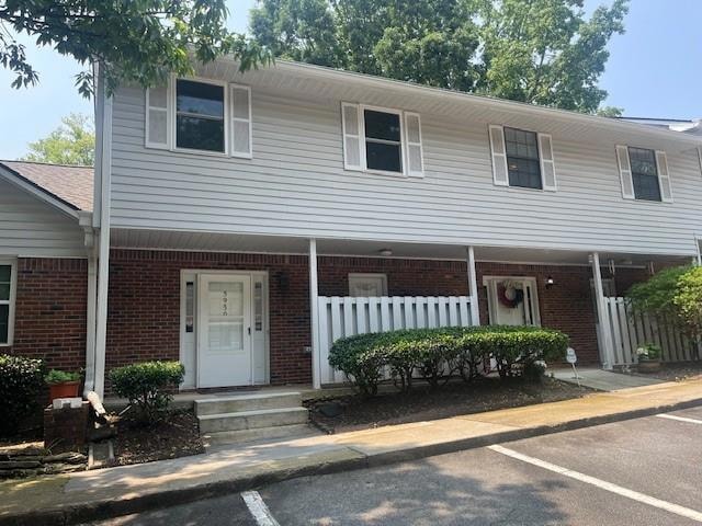 Multi unit property with brick siding, uncovered parking, and covered porch