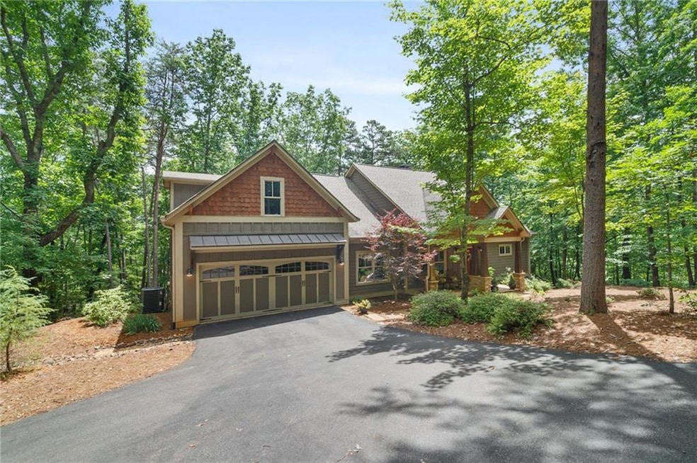 Craftsman-style house with a standing seam roof, asphalt driveway, a garage, central AC unit, and metal roof