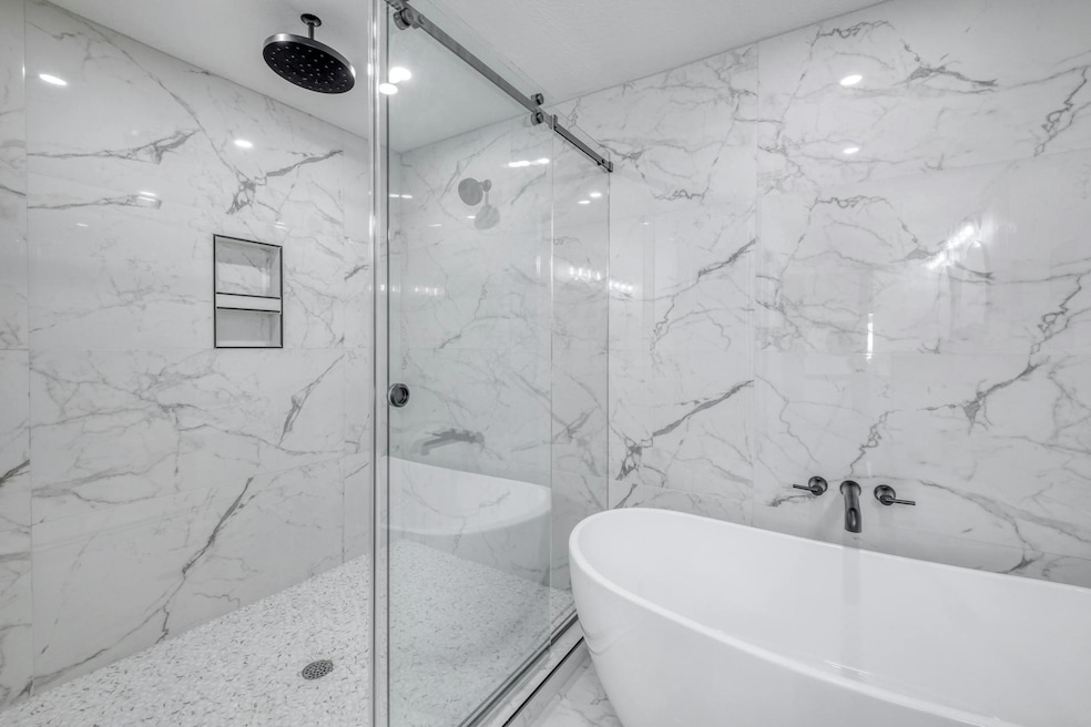 Bathroom with a marble finish shower, a freestand