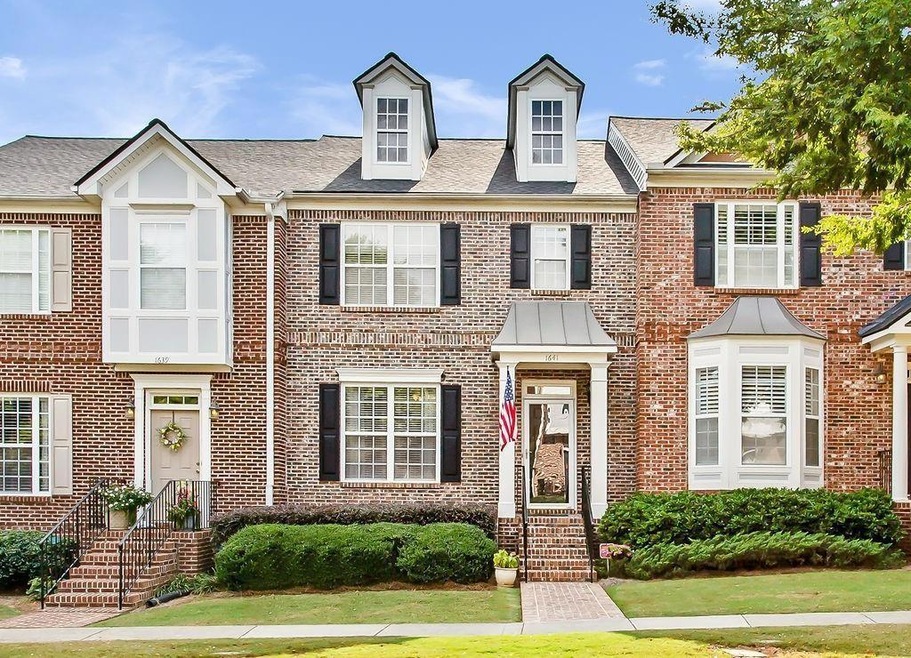 View of property with brick siding and a front lawn