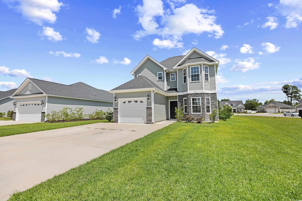 View of front of property featuring stone siding, concrete driveway, a front lawn, and a garage